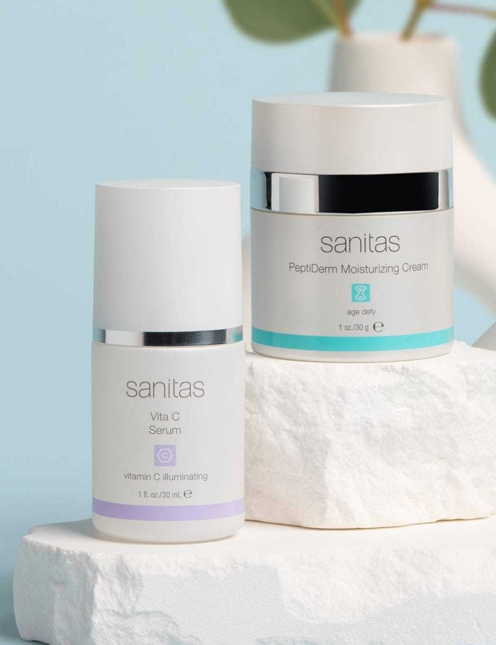Skincare products with white and silver packaging on a textured white surface.