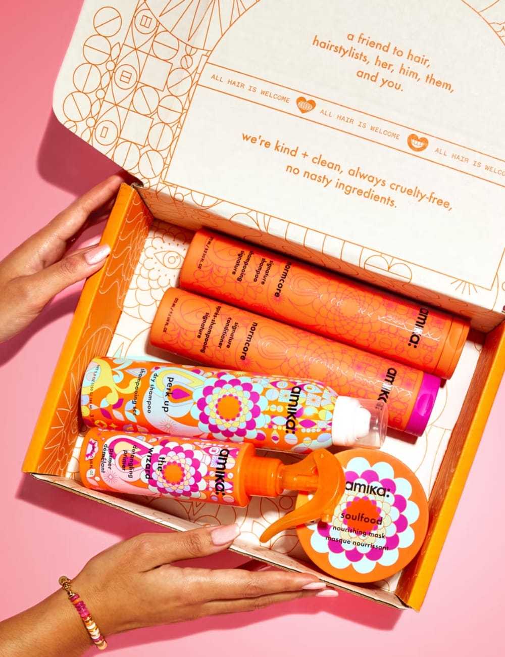 Open box with colorful hair care products labeled Amika. Bright, patterned packaging on display.